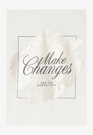 Tessuto di cotone bianco con una stampa metallica oro raffigurante il testo "Make Changes" all'interno di un contorno quadrato, con testo aggiuntivo sottostante.