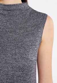 Bezramkowa bluzka w ciemnoszarym, strukturalnym dzianinowym materiale z dekoltem typu mock neck i gładkim wykończeniem. Brak widocznych elementów metalowych i wzorów.