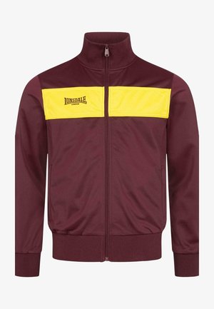 Bordo užtrauktukinė striukė su geltonu panešimu per krūtinę, su logotipu. Pagaminta iš lygaus audinio, turi elastingas rankoves.