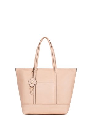 Borsa tote in pelle beige con manici lunghi, una tasca frontale e un ciondolo a forma di fiore attaccato a un manico.
