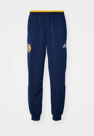 Navy athletic pants with yellow elastic waistband, featuring Real Madrid logo on the left thigh and Adidas logo in white on the right.