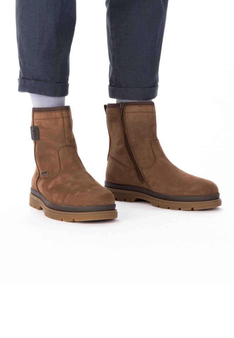 Bruine suède enkellaarzen met een zijrits, rubberen zool en gevoerde kraag; gestructureerd lijf en versterkte hak voor duurzaamheid.