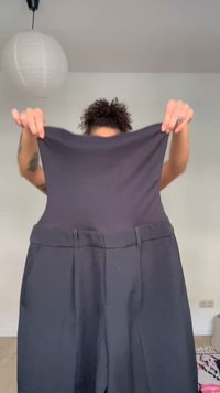 Personne tenant un pantalon gris foncé, montrant la ceinture étirée pour démontrer l'élasticité du tissu.