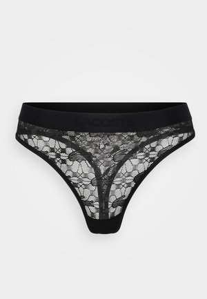 Must mustriba mustapitsi mustal laiad vöö, millel on reljeefne "Lacoste" logo, lille- ja võrkpinnad, V-kujuline disain ning õhukesed külgedel.