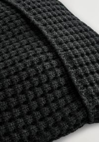 Schwarze strukturierte Decke mit einem Waffelmuster und einem leicht flauschigen Aussehen. Das Material ist weich und die Kanten sind sauber verarbeitet.