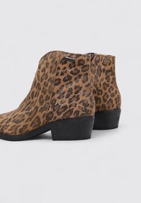 Bottines à imprimé léopard en tissu texturé, avec un talon noir et une fermeture éclair sur le côté, dotées d'un bout arrondi.