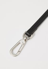 Curea din piele neagră cu clips metalic argintiu. Curea este îngustă și netedă, cu cusături curate; clipsul are un design clasic de carabină.