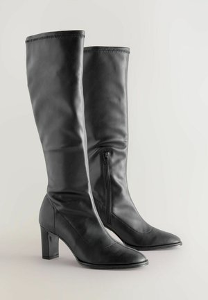 Svarta läderknähöga stövlar med spetsiga tår, blockklackar, subtil söm och sidodragkedjor för enkel påtagning. Slät textur.