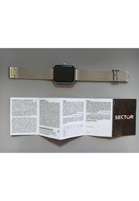 Orologio con cinturino in rete argentata e quadrante nero rettangolare, include un manuale di istruzioni piegato intitolato "SECTOR NO LIMITS" che presenta le informazioni sulla garanzia.