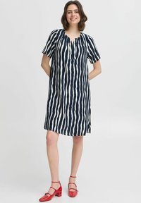 Rochie bleu marin cu dungi albe, cu mâneci scurte, decolteu în formă de V și slituri laterale. Purtați cu pantofi cu toc roșii pentru contrast.