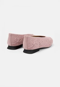Rosa tygballetskor med en strukturerad design, broderade detaljer och en liten svart klack.