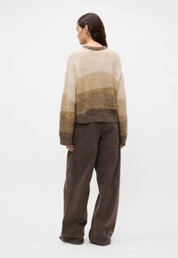Μπεζ και καφέ ριγέ πουλόβερ με κοντό κόψιμο, πλεκτή υφή και ριμπ μανσέτες, συνδυασμένο με αέρινες καφέ παν trousers.