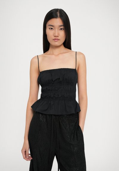 Top peplum negru cu bretele ajustabile, textură pliată și finisaj neted. Asortat cu pantaloni lejeri negri cu textură.