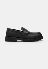 Mocassin en cuir noir avec détail tissé texturé sur la tige et semelle crantée épaisse, présenté de profil sur fond blanc.