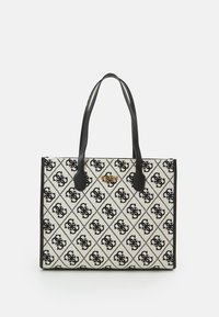 Rechthoekige beige draagtas met zwarte handgrepen, voorzien van een herhalend zwart monogrampatroon en een klein gouden "GUESS EST. 1981"-logo aan de voorkant.