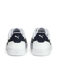 Sapatilhas brancas com detalhes em azul marinho, apresentando um painel de calcanhar em camurça, colarinho acolchoado e entressola texturizada, exibindo o logótipo da Puma.