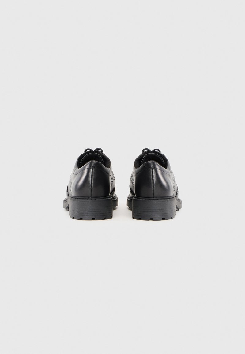 Zapatos de cuero negro con un acabado suave, punta redondeada y acentos texturizados en los laterales. Suela de goma gruesa con un patrón de tracción ligero.