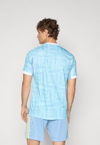 Jersey atlético color azul claro con un patrón abstracto texturizado, mangas cortas con ribetes blancos, acompañado de pantalones cortos matching en azul claro.