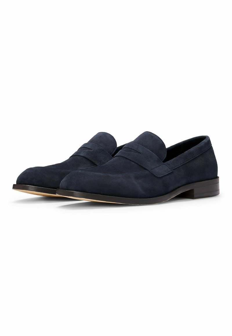 Mocassins en daim bleu marine avec un bout rond, des détails cousus et un talon bas. Texture lisse et sans accents métalliques visibles.