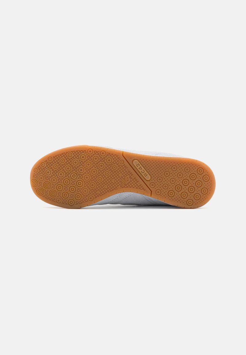 Baskets blanches avec une tige texturée et une semelle en caoutchouc orange. La semelle présente des motifs circulaires pour l'adhérence et le confort.