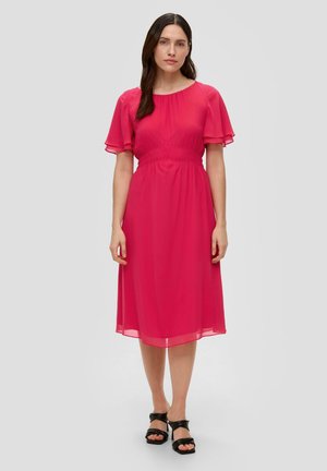 Roze chiffon jurk met korte gerimpelde mouwen, gerimpelde taille en een knielange zoom. Gepaarde met zwarte sandalen met blokhak.