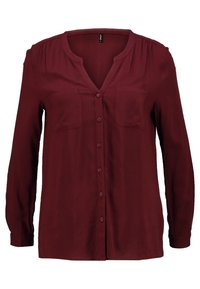 Blusa bordeaux a maniche lunghe con bottoni frontali, due tasche sul petto e colletto a V arrotondato.