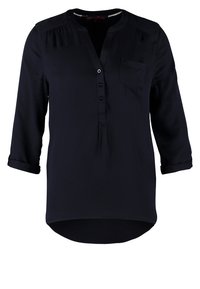 Marinblus, lättviktigt tyg, V-ringning, fem knappar, trekvartslånga ärmar och en enda bröstficka med uppvikta ärmslut.