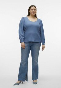 Lyseblå tekstureret bluse med puffærmer, parret med lys denim jeans med flared ben og sideslids, samt blå spidse hæle.