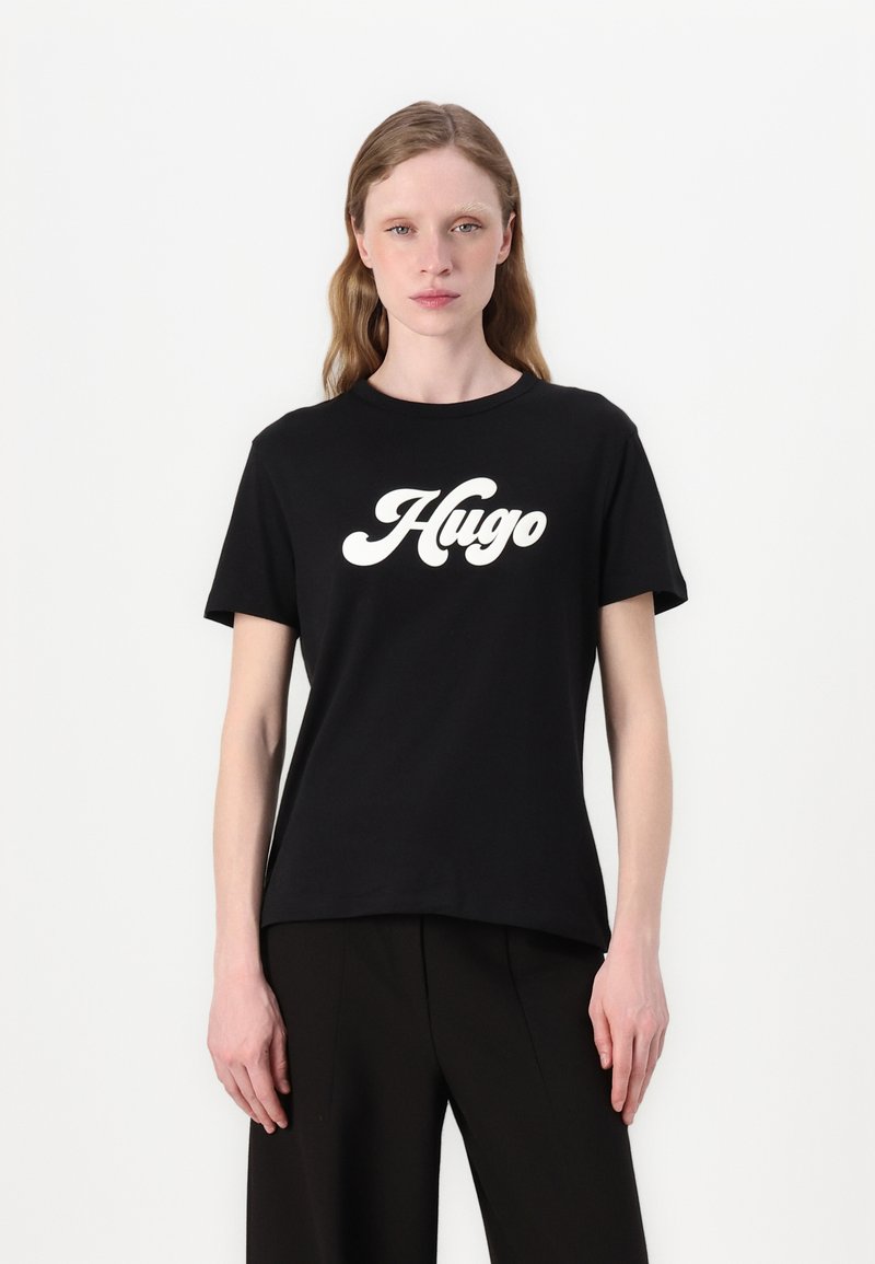Černé bavlněné tričko s kulatým výstřihem. Má velké bílé logo "Hugo" v kurzívě. Krátké rukávy a volný střih.