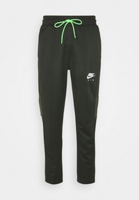 Pantalones deportivos negros hechos de una tela suave, con un cordón verde neón y bolsillos laterales con acentos de color verde oliva. Logo de Nike Air mostrado.