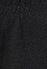 Schwarzer Strickstoff mit glatter Textur und einem dezenten Stretch. Nahtdetails sind am Bund sichtbar. Keine Muster oder Akzente.