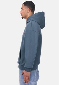 Sweat à capuche en coton mélangé gris foncé. Comprend une poche kangourou et des poignets côtelés. Logo brodé en rose sur la poitrine.