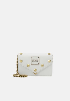 Hvid Versace Jeans Couture clutch med gyldne nitter, en frontlogo-plade og en guldkæde strop på en hvid baggrund.