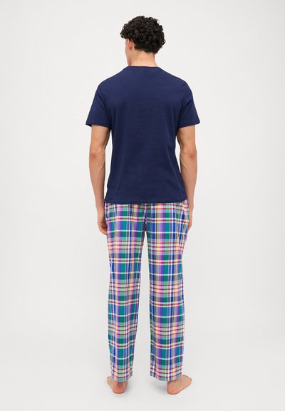 T-shirt de algodão azul-marinho combinado com calças de pijama de xadrez multicoloridas, apresentando padrões de quadrados em azul, verde, rosa e branco, com um corte confortável.