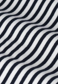 Textiel met zwarte en witte golvende strepen. Het oppervlak heeft een geribbelde textuur, wat de fluiditeit en het contrast van het patroon benadrukt.