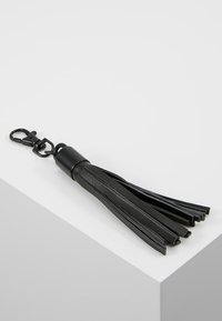 Svart läder nyckelring med tofsar har flera fransar, en rund metallfäste och en krok för enkel fäste.