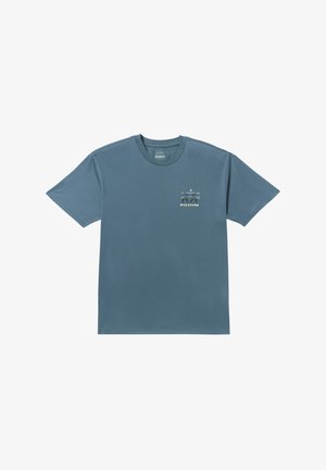 T-shirt in cotone blu con maniche corte, collo a giro, e una piccola stampa grafica in beige e verde sul lato sinistro del petto.