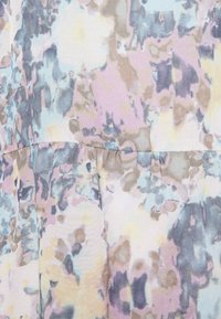 Tissu léger présentant un motif floral abstrait dans des couleurs pastel de rose, bleu et beige ; texturé avec des coutures froncées.