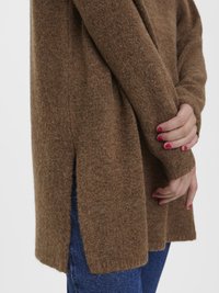 Brown knit sweater featuring a soft texture, ribbed cuffs, and side slits for ease of movement, paired with blue denim.