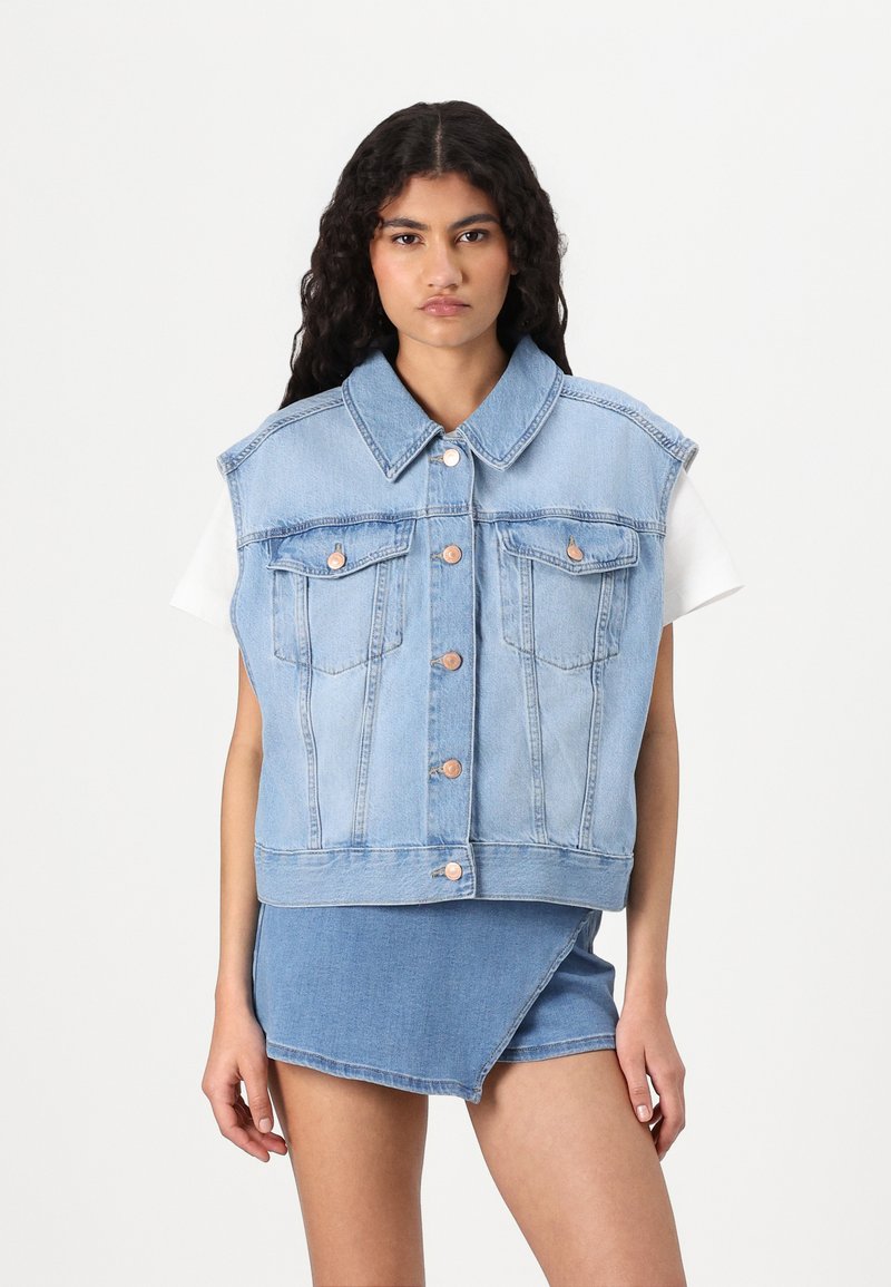 Gilet in denim azzurro chiaro con colletto, design senza maniche, tasche frontali e bottoni di tonalità rame, abbinato a una gonna in denim coordinata.