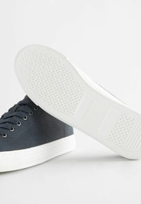 Baskets montantes navy en tissu texturé avec semelle en caoutchouc blanc. Présentent des lacets ronds et un motif de semelle pour une meilleure adhérence.