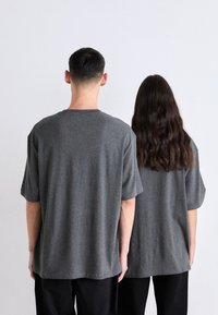 Camisetas grises de manga corta, hechas de una tela suave, que presentan un corte relajado y un diseño de cuello redondo, vistas desde la parte de atrás.
