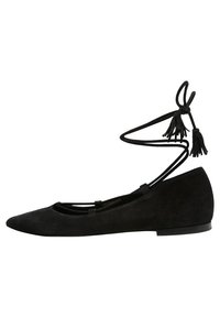 Bailarinas de ante negro con punta afilada, que cuentan con una delicada correa de tobillo con lazo y borlas, y una suela plana.