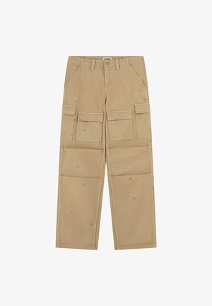 Beige cargo pants with multiple front and side pockets, featuring a relaxed fit, light wear marks, and a zipper fly closure.