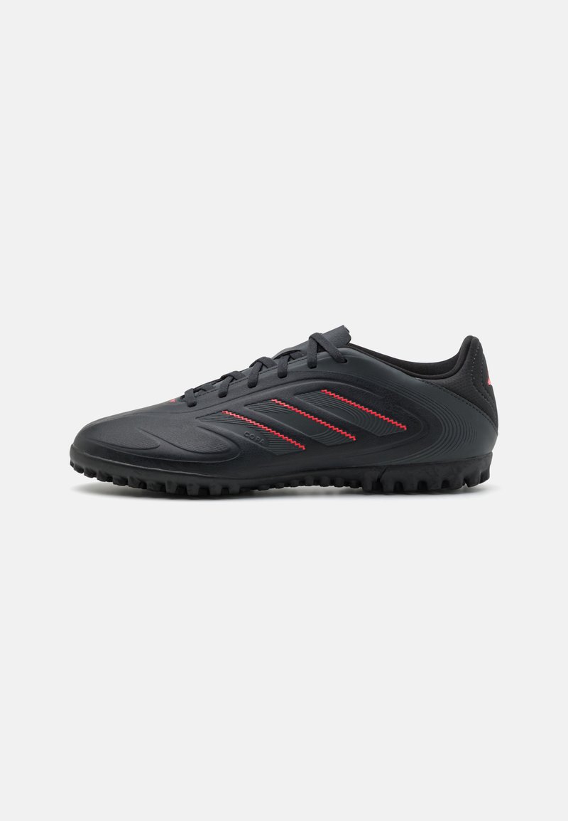 Black athletic shoes with red accents, featuring a smooth upper material, lace closure, and textured rubber sole with prominent studs.