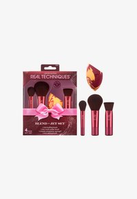 Ensemble de pinceaux de maquillage de quatre pièces dans une boîte transparente. Les pinceaux ont des poignées métalliques roses. Comprend une éponge texturée jaune et bordeaux. Accent de ruban cadeau.