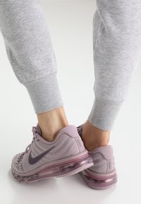 Zapatillas Nike Air Max en malla de color púrpura claro con un acabado texturizado, que cuentan con una suela de amortiguación de aire transparente y un logo de color púrpura oscuro.
