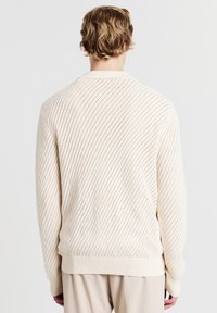 Maglione leggero in crema con motivo a diamante, con polsini e orlo a coste, caratterizzato da una vestibilità rilassata e una texture morbida.