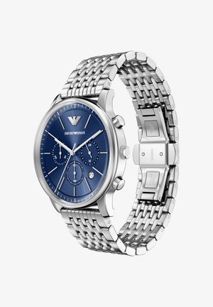 Srebrny zegarek ze stali nierdzewnej z niebieską teksturowaną tarczą, trzema subtarcza i plecioną bransoletą. Posiada zapięcie motylkowe i detal z logo.