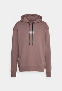 Sweat à capuche mauve avec un panneau texturé et des cordons de serrage noirs contrastants. Présente un graphisme réfléchissant au centre.